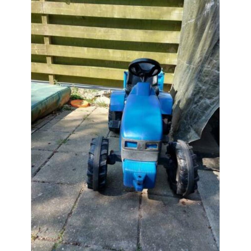 Blauwe tractor met aanhanger die omhoog kan.